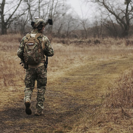 jeune militaire en tenue de camouflage qui marche dans la forêt