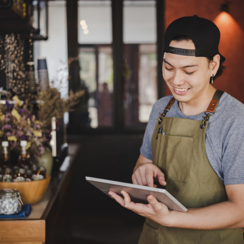 jeune barman asiatique tenant une tablette pour prendre les commandes dans un café